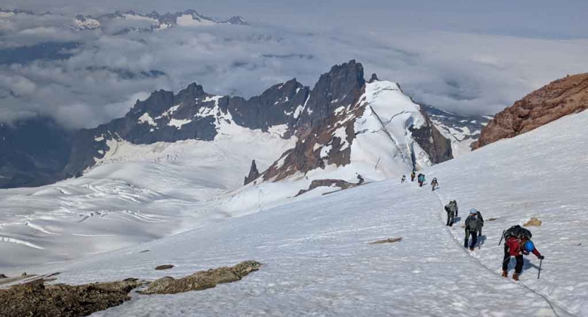 a group of students on a mountaineering course traverse a snowy mountainous landscape